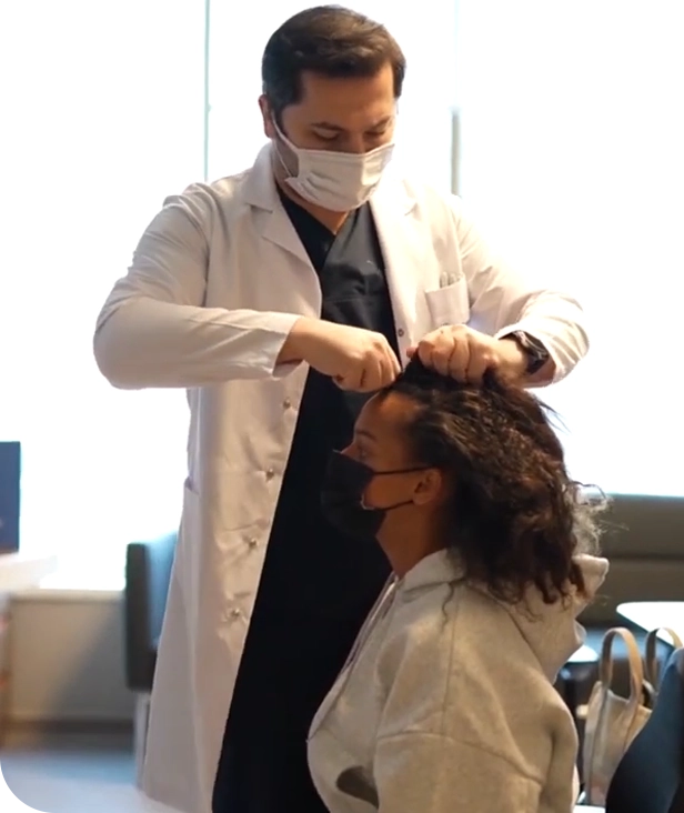 الدكتور عبد العزيز بلوي، أفضل دكتور زراعة شعر في تركيا، يُجري فحصًا دقيقًا لحالة شعر إحدى المريضات داخل مركز Elithair في إسطنبول، وذلك لتحديد الخطة الأنسب لزراعة الشعر باستخدام أحدث التقنيات مثل FUE أو DHI. تعكس الصورة العناية الشخصية والخبرة العالية التي تميز الدكتور عبد العزيز وفريقه الطبي.